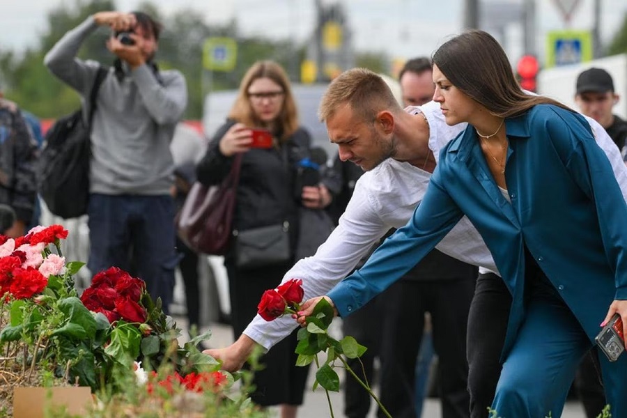 Un grupo de personas deposita flores en la sede de Wagner en San Petersburgo tras el accidente aéreo